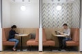 Two young freelancers working seated at tables in modern coworking