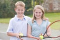 Two young friends on tennis court smiling Royalty Free Stock Photo