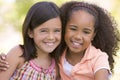 Two young girl friends sitting outdoors