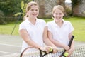 Two young girl friends on tennis court smiling Royalty Free Stock Photo