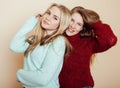 Two young girlfriends in winter sweaters indoors having fun. Lifestyle. Blond teen friends close up Royalty Free Stock Photo