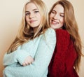 Two young girlfriends in winter sweaters indoors having fun. Lifestyle. Blond teen friends close up Royalty Free Stock Photo