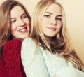 Two young girlfriends in winter sweaters indoors having fun. Lifestyle. Blond teen friends close up Royalty Free Stock Photo
