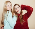 Two young girlfriends in winter sweaters indoors having fun. Lifestyle. Blond teen friends close up Royalty Free Stock Photo