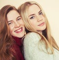 Two young girlfriends in winter sweaters indoors having fun. Lifestyle. Blond teen friends close up Royalty Free Stock Photo