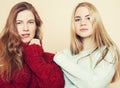 Two young girlfriends in winter sweaters indoors having fun. Lifestyle. Blond teen friends close up Royalty Free Stock Photo