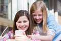 Two Young Girls At Cafe Reading Text Message On Mobile Phone Royalty Free Stock Photo