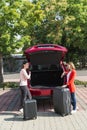 Two girls brought suitcases to open trunk of car Royalty Free Stock Photo