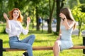 Two young girls friends sitting on a bench in summer park talking happily having fun Royalty Free Stock Photo