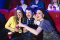 Two young girls and a guy watching a comedy in a cinema. Young friends watching movie in cinema. Group of people in Royalty Free Stock Photo