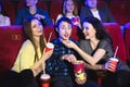 Two young girls and a guy watching a comedy in a cinema. Young friends watching movie in cinema. Group of people in Royalty Free Stock Photo