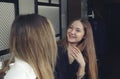 Two young girls are happy and laughing have a tea time at the counter in a cafe