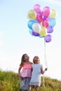 Two Young Girls Holding Bunch Of Colorful Balloons Outdoors Royalty Free Stock Photo