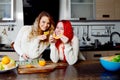 Two young girls in the kitchen talking and eating fruit, healthy lifestyle Royalty Free Stock Photo