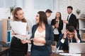 Two young girls are laughing at work annoying boss. Young pregnant woman in office with colleague.