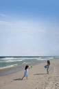 Two young girls playing on a beach coast by the sea waters on the sand with a plastic bucket Royalty Free Stock Photo