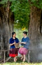 Two young girls prepare food using motar and other flavoring look like to make papaya salad and they look to each other under big