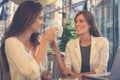 Two young girls sitting in cafe drinking coffee and having conversation. Royalty Free Stock Photo