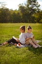 Two young girls sitting on green grass outdoors reading separate books. Friends enjoying time together in summer in park Royalty Free Stock Photo
