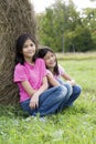 Two young girls sitting by haybale