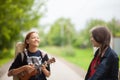 Two young girls walking together, laughing and playing ukulele