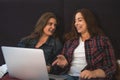Two young girls or women laughing and discussing something using laptop, female lesbian couple spend time together Royalty Free Stock Photo