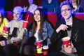 Two young guys and a girl watching a Comedy in a movie theater. Young friends watch movies in the cinema. Group of Royalty Free Stock Photo