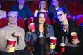 Two young guys and a girl watching a Comedy in a movie theater. Young friends watch movies in the cinema. Group of Royalty Free Stock Photo