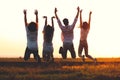 Two young guys and two girls are holding their hand and jumping in the field on a summer day. Back view. Royalty Free Stock Photo