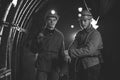 Two young guys in special clothes and helmets standing in the mine