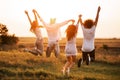 Two young guys and two girls are holding their hand and jumping in the field on a summer day. Back view. Royalty Free Stock Photo