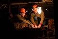 Two young guys in a working uniform and protective helmets, sitting in a low tunnel. Workers of the mine