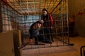 Two young Halloween victims imprisoned in a metal cage, boy pull