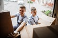 Two young handsome smiling movers wearing uniforms are unloading the van full of boxes. House move, mover service