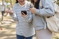 Two young happy Asian female college students are looking at a smartphone screen together Royalty Free Stock Photo