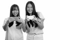 Two young happy Asian teenage girls smiling and taking picture with mobile phone Royalty Free Stock Photo