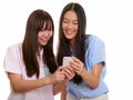 Two young happy Asian teenage girls smiling and using mobile pho Royalty Free Stock Photo