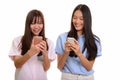 Two young happy Asian teenage girls smiling and using mobile pho Royalty Free Stock Photo