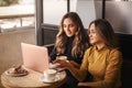 Two young happy attractive women business partners using at laptop at meeting in cafe Royalty Free Stock Photo