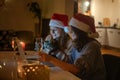 Two young happy beautiful women girlfriends lesbian couple with glasses of champagne in red santa hats celebrate new Royalty Free Stock Photo