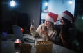 Two young happy beautiful women girlfriends lesbian couple with glasses of champagne in red santa hats celebrate new Royalty Free Stock Photo