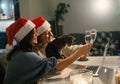 Two young happy beautiful women girlfriends lesbian couple with glasses of champagne in red santa hats celebrate new Royalty Free Stock Photo