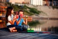 Two young happy little friends, boy and girl talking, drinking tea, eating sandwiches and fishing on a lake in a sunny summer day Royalty Free Stock Photo