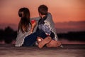 Two young happy little friends, boy and girl talking while sitting covered with blanket during sunset Royalty Free Stock Photo