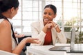 Two young happy mixed race businesswomen having a meeting in a boardroom at work. Cheerful businesspeople talking while Royalty Free Stock Photo