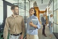 Two young happy multiracial male and female coworkers talking and smiling while walking in the modern office Royalty Free Stock Photo