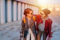 Two young happy short-haired women strolling together, holding their skateboards Royalty Free Stock Photo