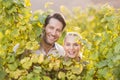 Two young happy vintners looking at camera from behind grape plants Royalty Free Stock Photo