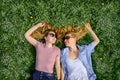 Two young happy women in a flowery meadow on sunny day, top view, close-up. Cheerful female friends lying on the lawn, looking at