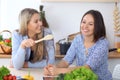 Two young happy women making online shopping for making menu by tablet computer. Friends cooking in the kitchen Royalty Free Stock Photo